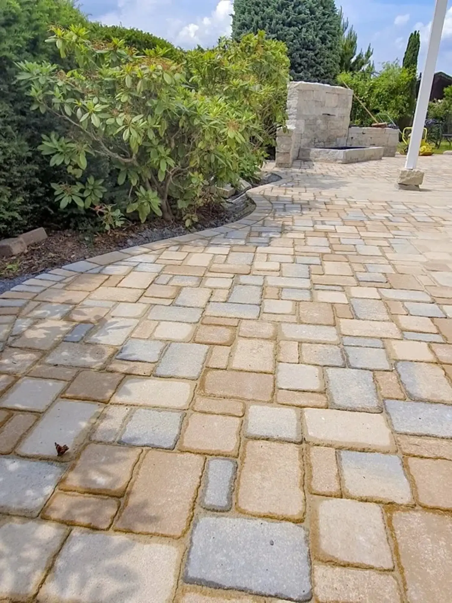 Gepflasterter Gartenweg aus hellbraunen und grauen Steinen