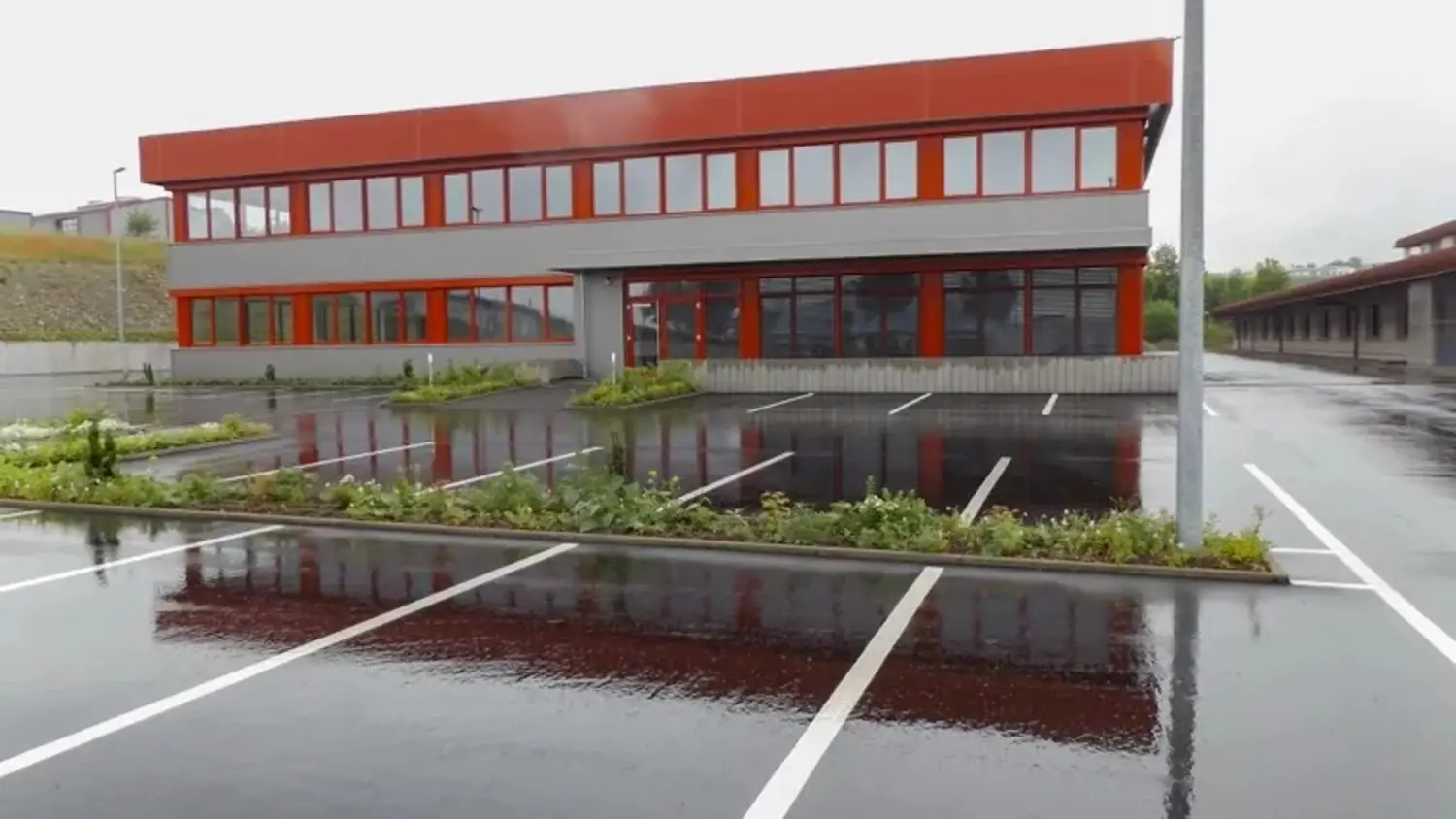 Modernes Bürogebäude mit Parkplatz und Pflanzenbeeten